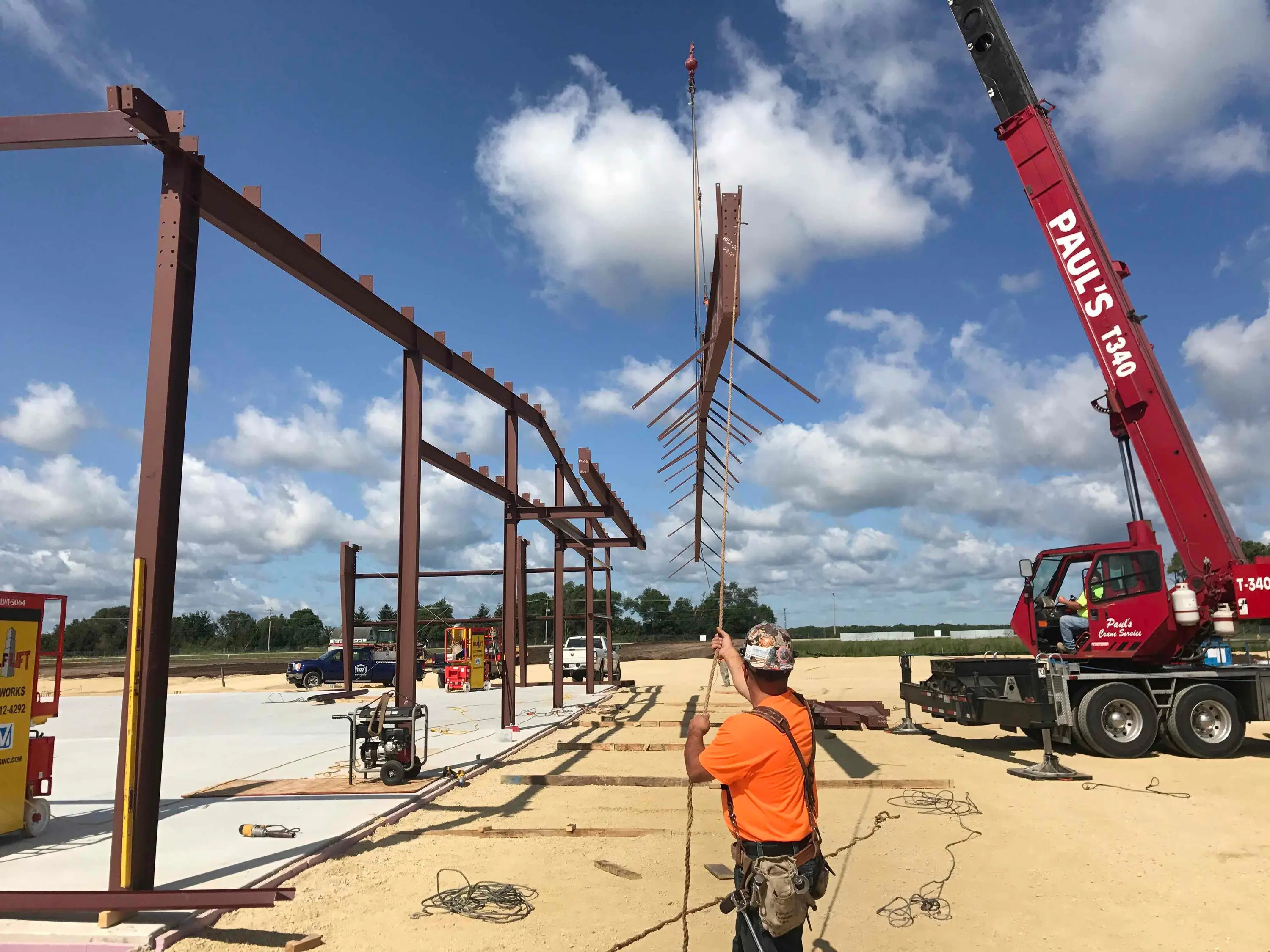 Crane lifting a steel beam into place on a building frame under construction