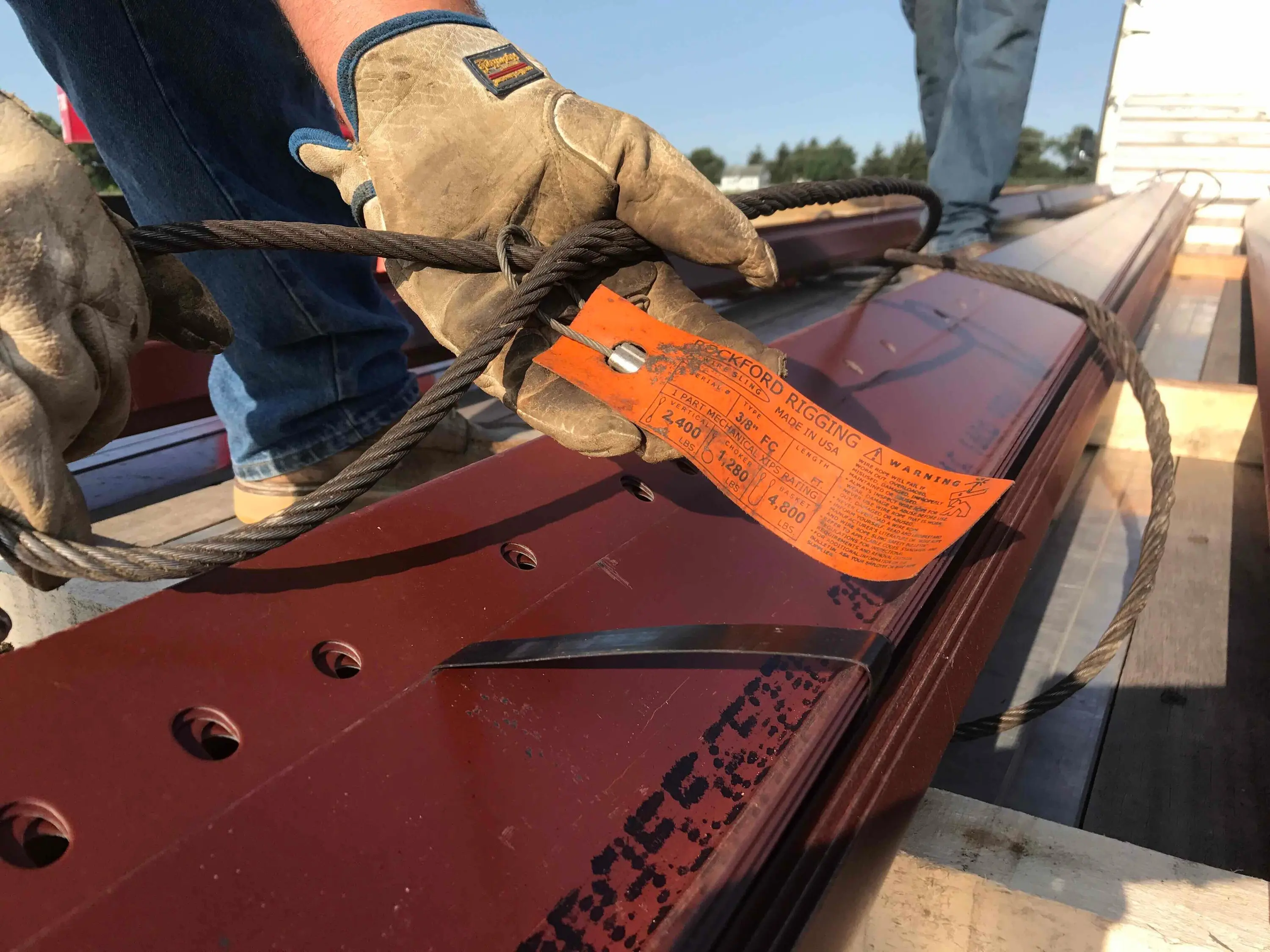 Ironworker rigging a steel beam with a tagged sling